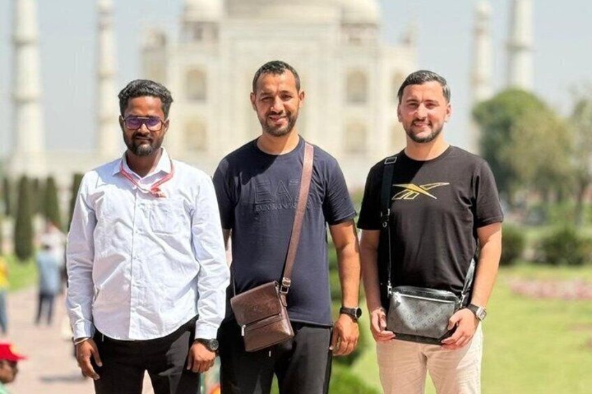 Three men standing in front of a large white building with domes. 2