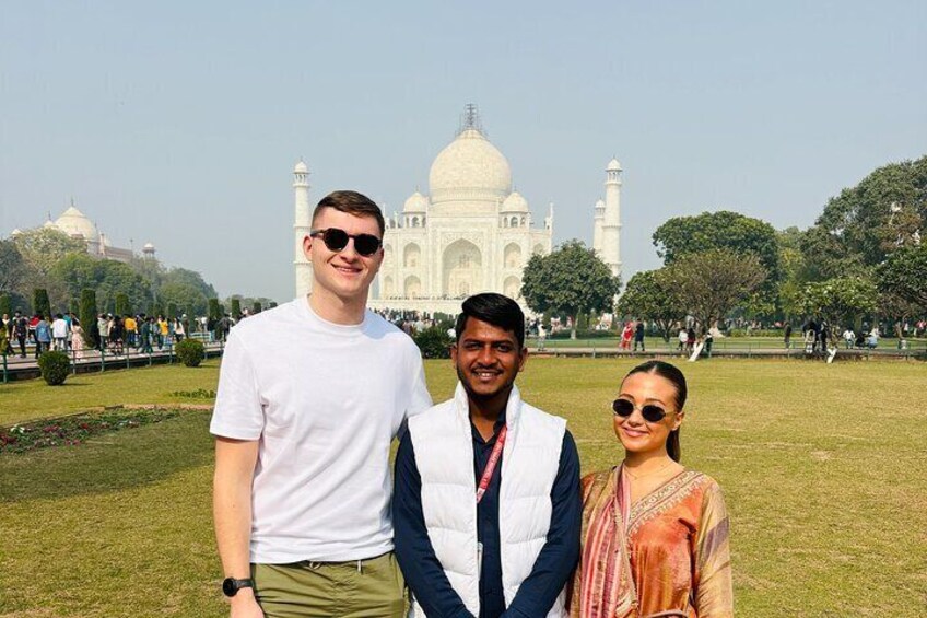 Three people standing in front of the Taj Mahal. 1