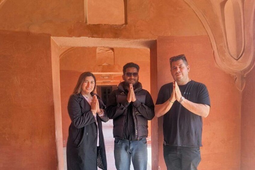 Three people standing in an arched doorway with their hands in a prayer position. 4