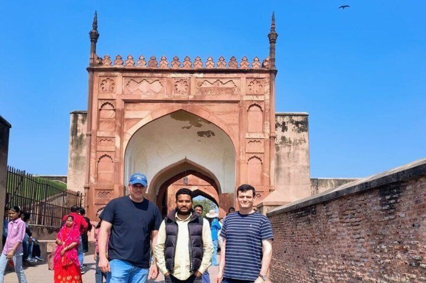 A group of people standing in front of a historic archway with intricate designs. 3