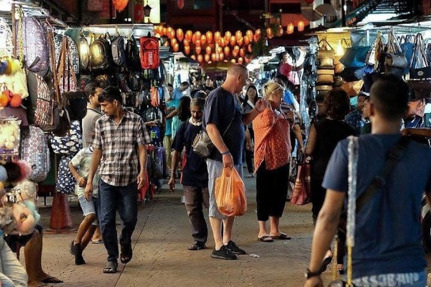 A crowded market with people walking and carrying bags. 3