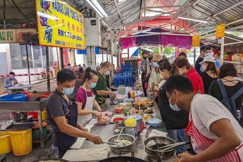 A bustling street food market with vendors preparing food. 1