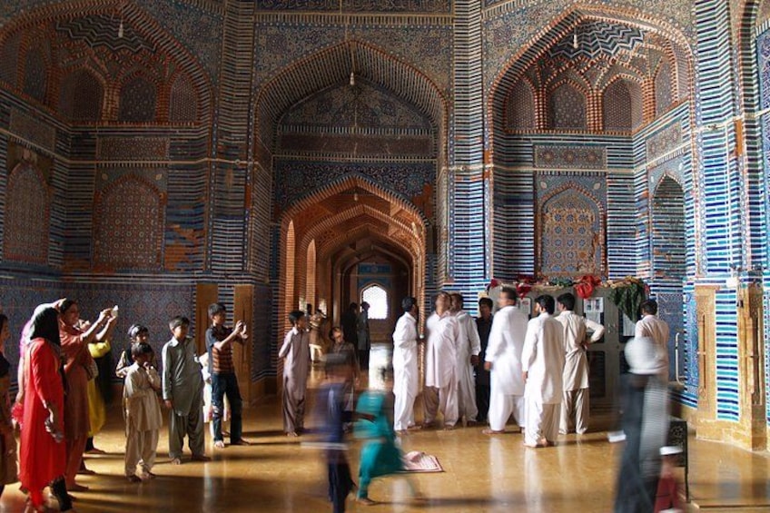 Un bâtiment historique remarquable, orné de motifs complexes en carreaux bleus et dorés, doté d’arcades et abritant un groupe de personnes vêtues de costumes traditionnels. 5