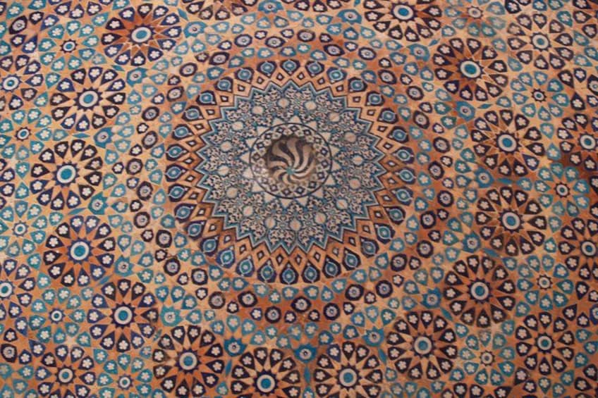 Une tapisserie richement décorée, avec un motif circulaire central entouré de motifs géométriques plus petits. 4