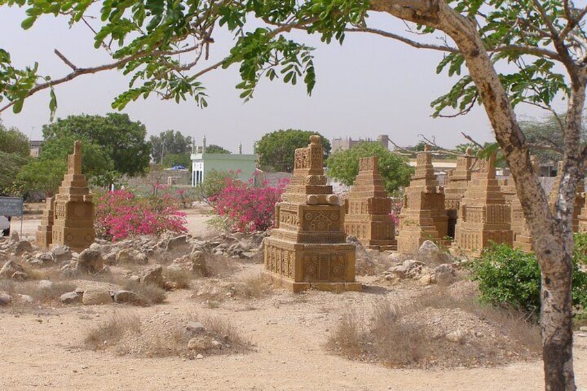 Ancient stone structures in a desert landscape with sparse vegetation and a distant building. 3