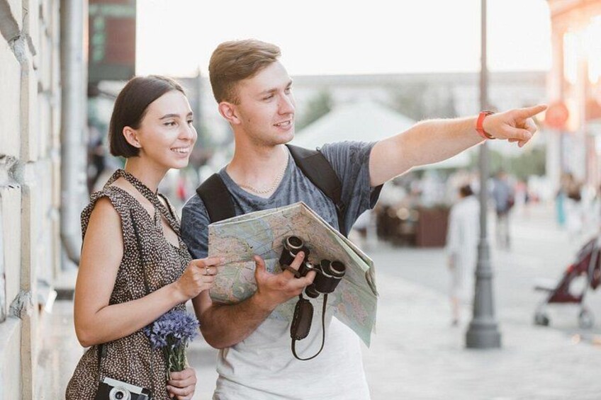 A couple holding a map and a camera, pointing at something off-camera. 5