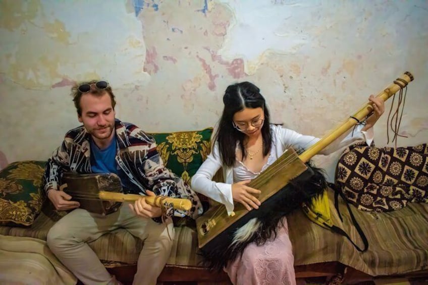 Two people sitting on a couch with a musical instrument. 2