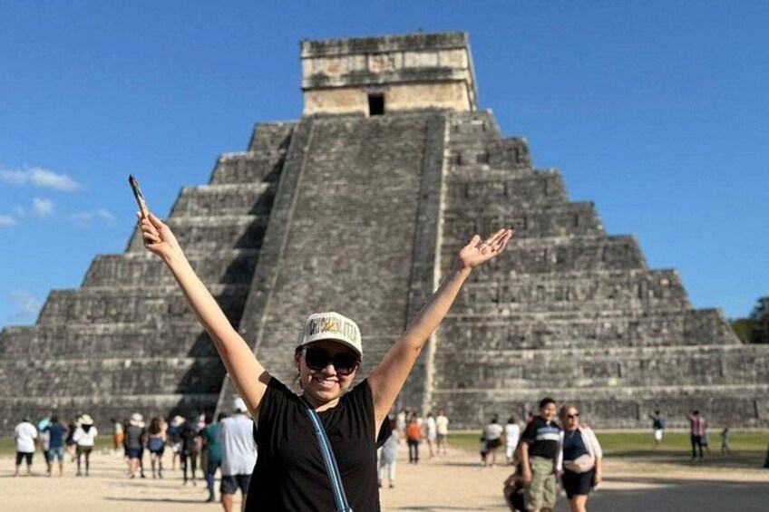 En person med armene i vejret foran en stor pyramide. 1