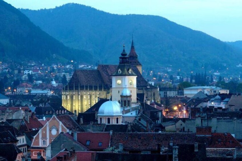 A town with a prominent church featuring a clock tower and a dome, surrounded by buildings and hills. 4