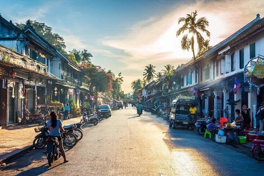 A street lined with traditional buildings, motorcycles parked along the sides, and a clear sky. 2