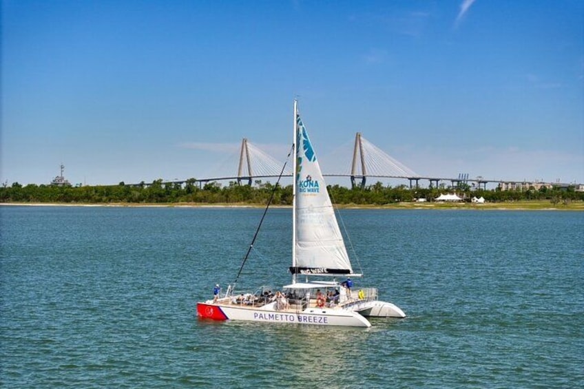 A sailboat named 'Palmetto Breeze' on a body of water with a bridge in the background. 4