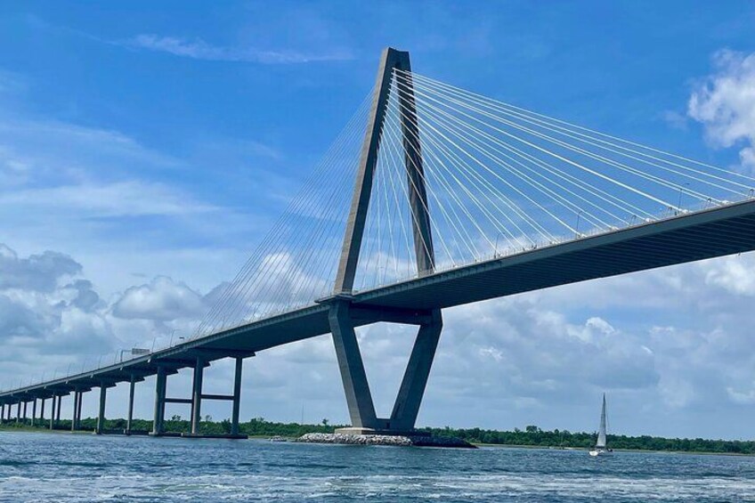 A cable-stayed bridge over water with a sailboat in the distance. 2
