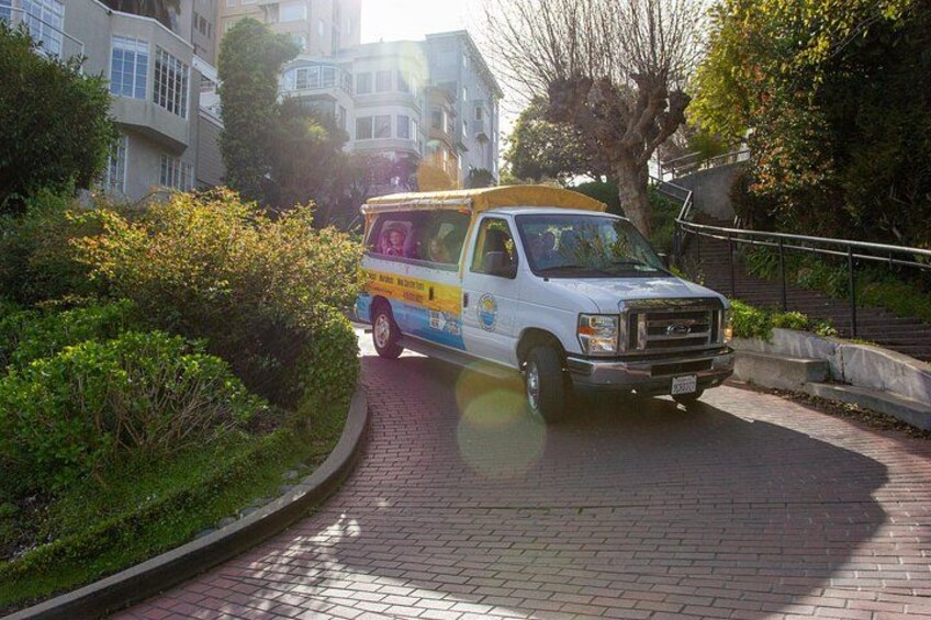 A white van with a colorful advertisement parked on a brick pathway. 2