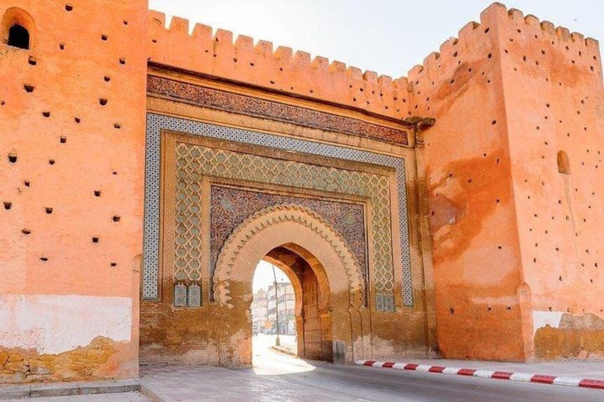 A historic archway with intricate tile work and a fortified wall. 1