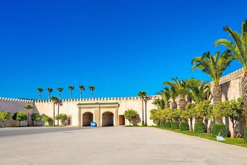 A large open courtyard with a historic building featuring arches and palm trees. 2