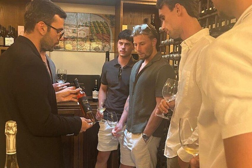 A group of people in a bar with wine bottles and glasses. 5