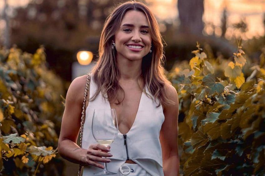 A person standing in a vineyard with rows of grapevines. 1