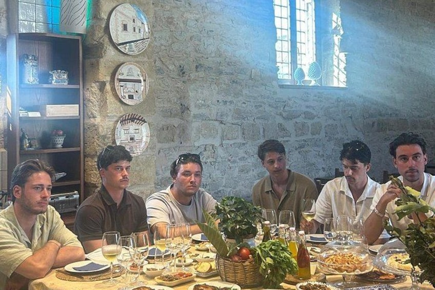 A group of people dining at a table with various dishes and drinks. 2