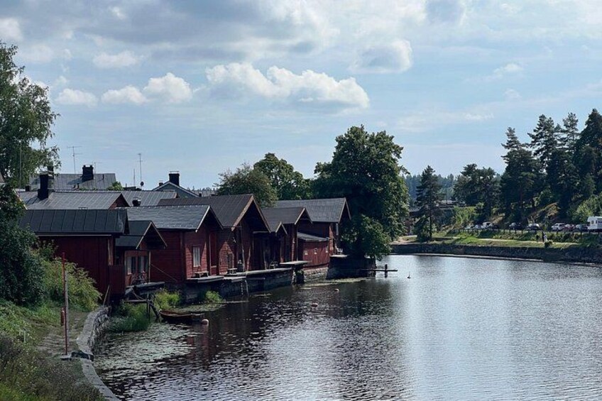 A row of red wooden houses by a calm lake with a dock extending into the water. 4