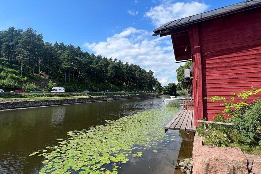 A red building by a calm river with lily pads and a dock. 3