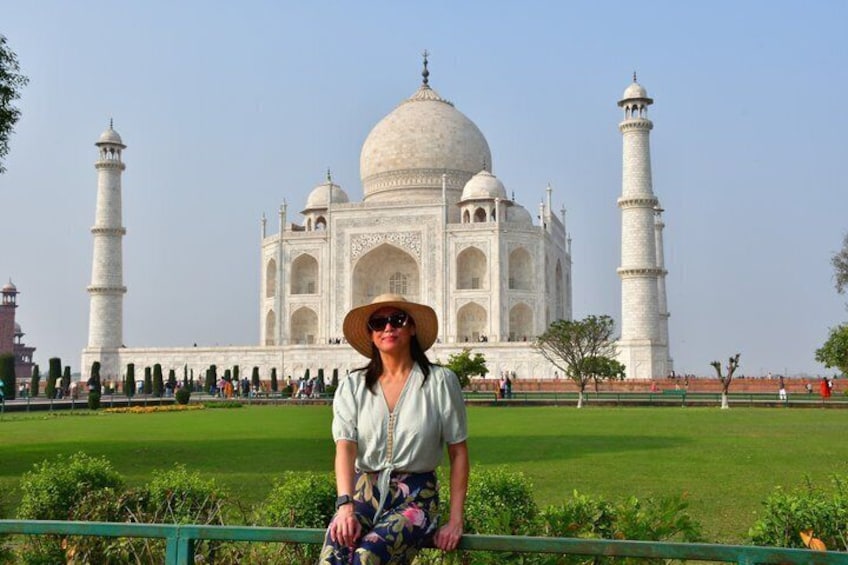 Eine Person steht vor dem Taj Mahal mit seinen vier Minaretten und der großen Kuppel. 1