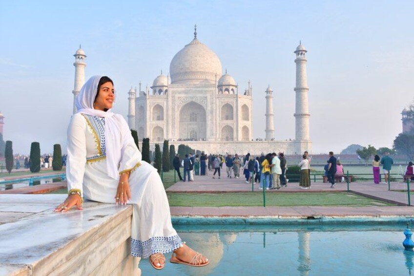 Eine Person sitzt auf einer Marmorbank mit dem Taj Mahal im Hintergrund. 2