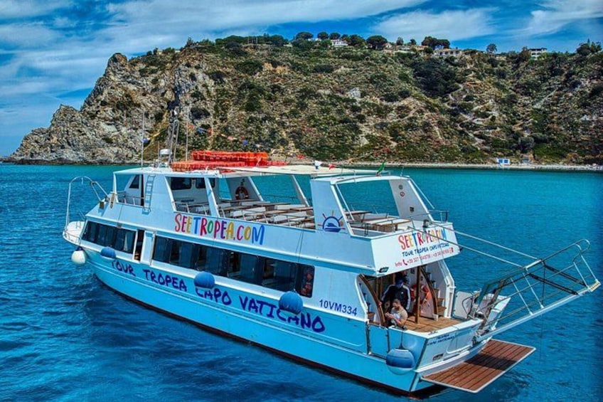 A boat named 'SEITROPEA.COM' on a body of water with a rocky coastline in the background. 3