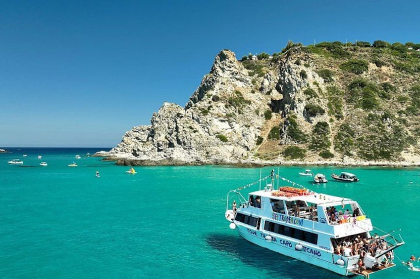A boat named 'Settepiragel' on turquoise waters with rocky cliffs in the background. 5