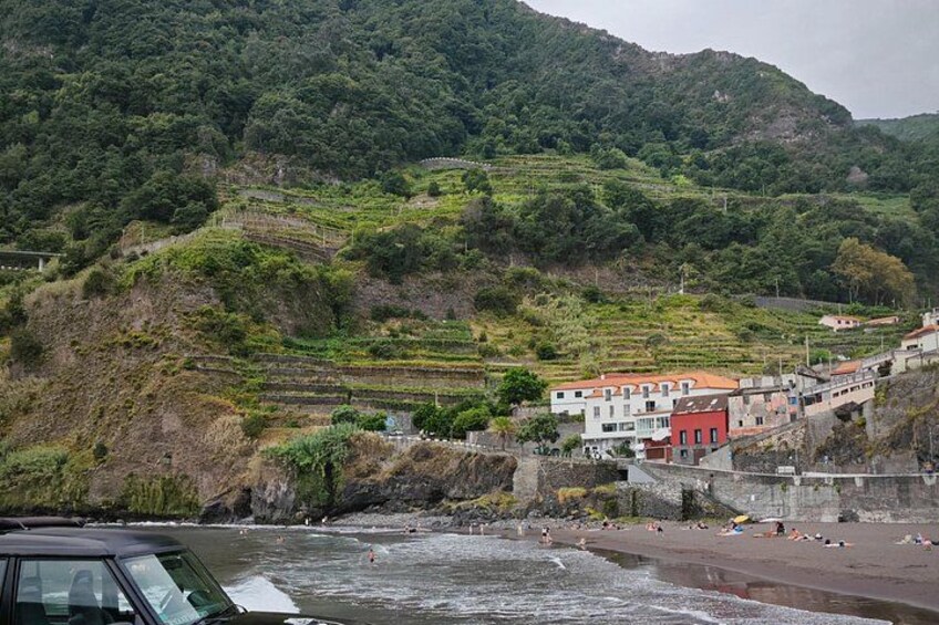 A coastal village with terraced vineyards, a beach, and a stone wall. 3