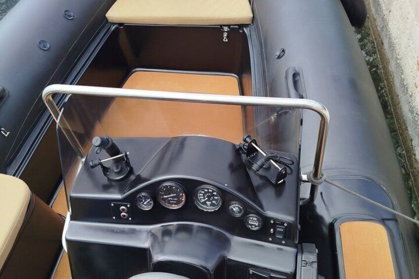A boat's control panel with gauges and a steering wheel. 4