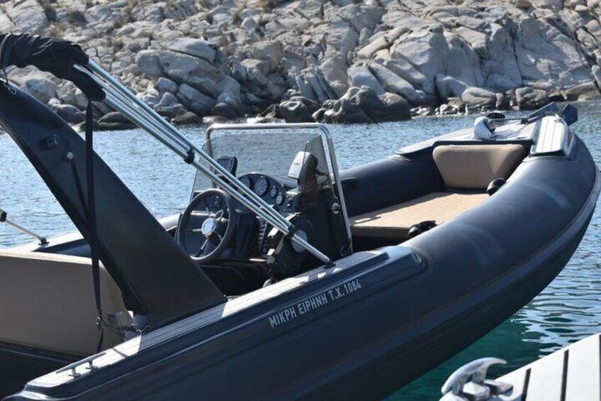 A motorboat with a steering wheel and a speedometer, docked near rocky shores. 2