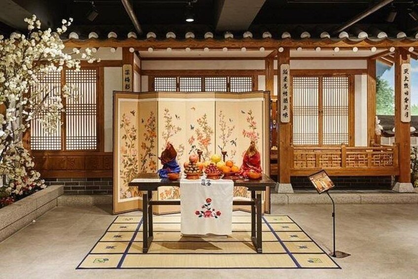 Un santuario japonés tradicional con estructura de madera, una mesa con ofrendas y un fondo de cerezos en flor. 2