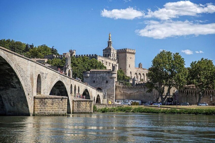 Un pont de pierre enjambant une étendue d’eau, un château avec une tour et un ciel bleu azur. 2