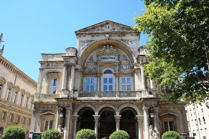 Un bâtiment historique doté d’une grande entrée en arc de cercle, de colonnes et d’une enseigne sur laquelle on peut lire « THÉÂTRE ». 1