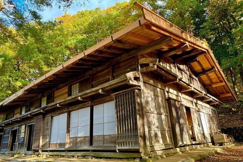 A traditional wooden building with a sloped roof, large windows, and a stone base, surrounded by trees. 3
