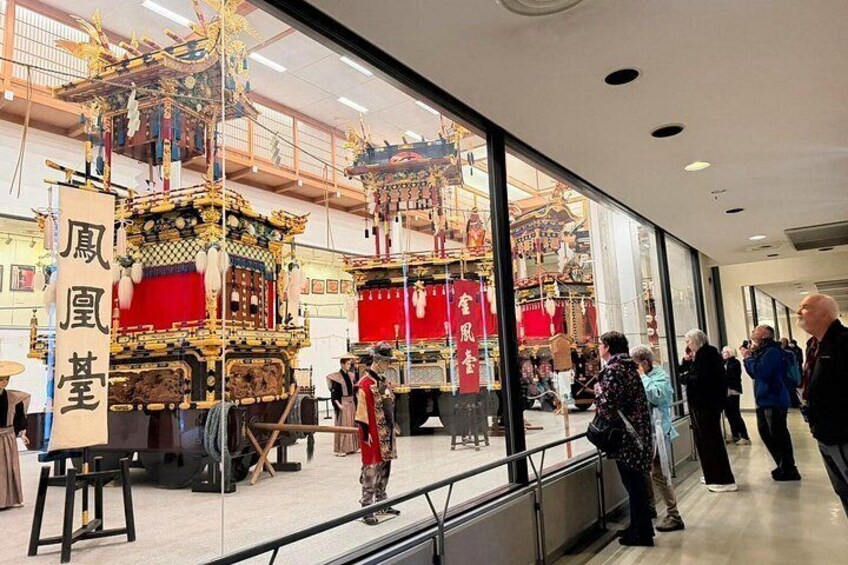 A traditional Chinese pavilion with intricate designs and red decorations, surrounded by onlookers. 2