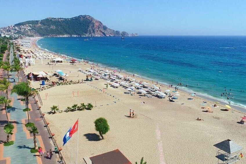 A coastal beach with umbrellas, a flag, and a clear blue sea. 5