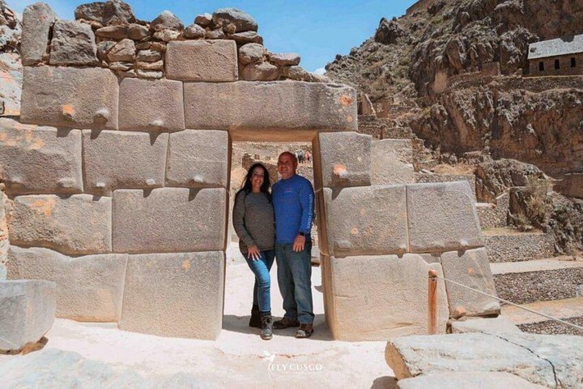 Un edificio in pietra con un portale, circondato da rocce grandi e un paesaggio montuoso. 3