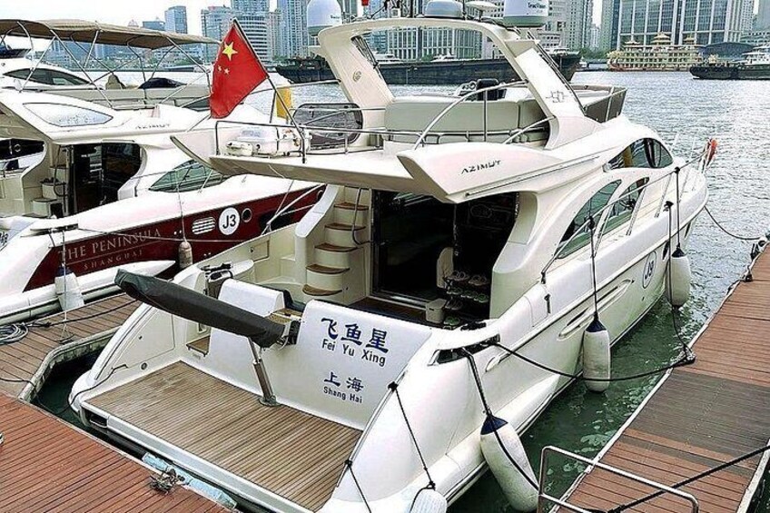 A white yacht docked at a marina with a sign in Chinese characters. 1
