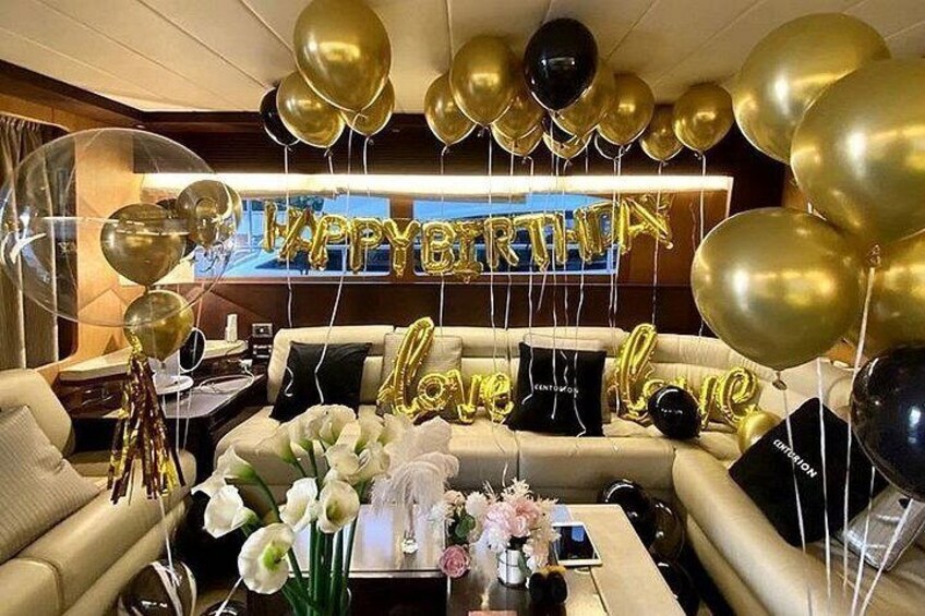 A living room with a sofa, a coffee table, and a TV. There are balloons and a 'Happy Birthday' sign. 4