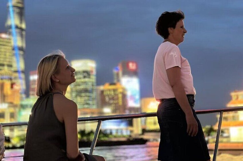 Dos personas en un balcón con vistas a una ciudad iluminada por la noche. 2