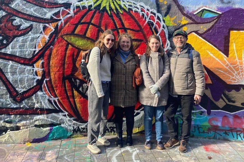 A group of people standing in front of a colorful graffiti wall. 3