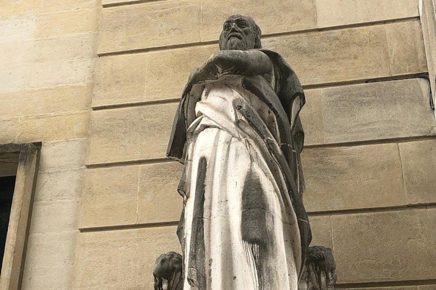 A statue of a person in a robe, standing on a pedestal with two smaller statues on either side. 4