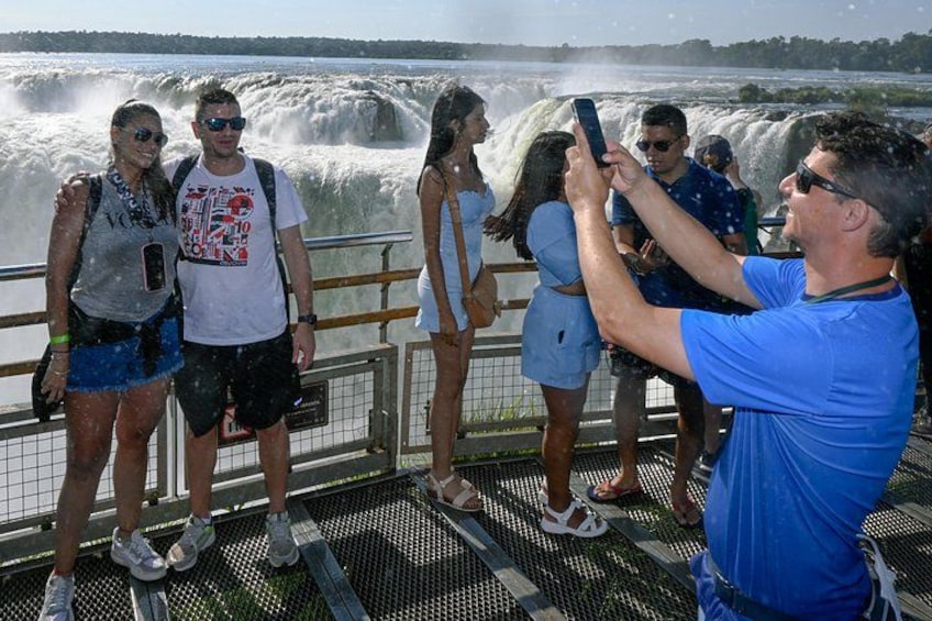 People standing on a boat deck, taking photos of a waterfall. 2