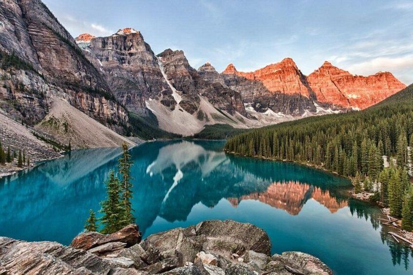 A mountain lake with clear reflections, surrounded by forest and rocky terrain. 3