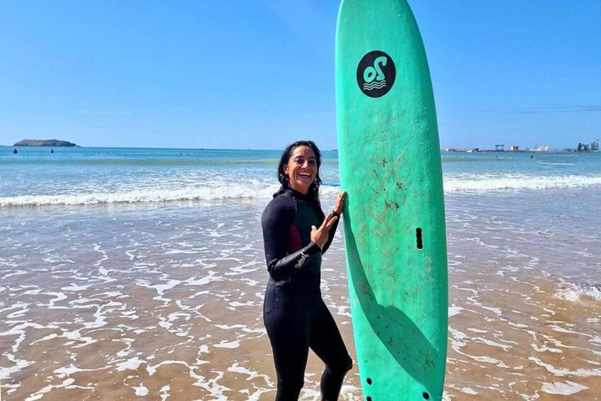 En person holder en surfbræt på en strand med bølger og en klar himmel. 5