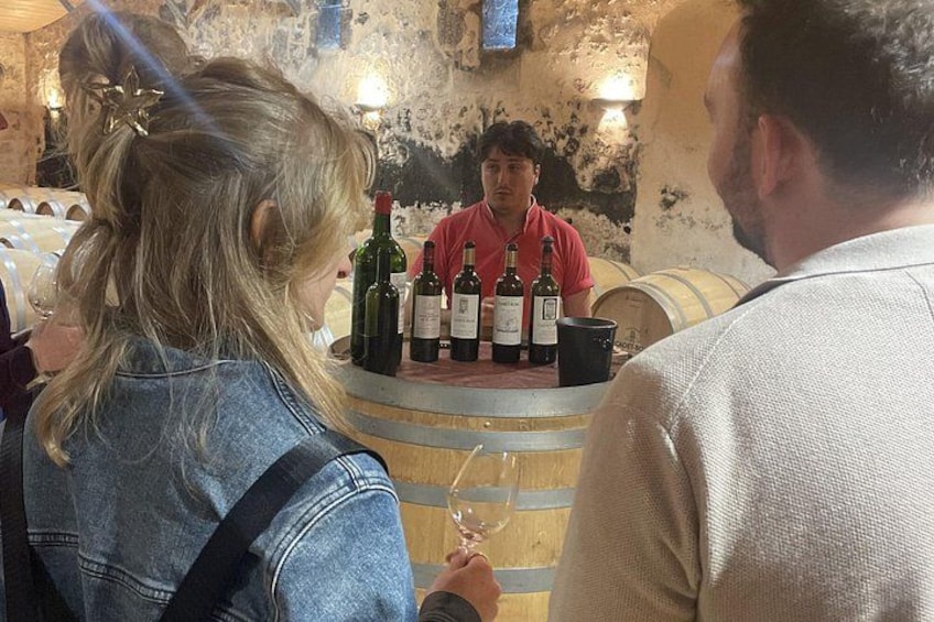 A wine tasting event with a bartender, wine bottles, and a barrel in the background. 5
