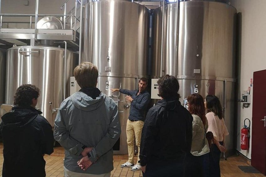 A group of people observing large stainless steel tanks in a facility. 5