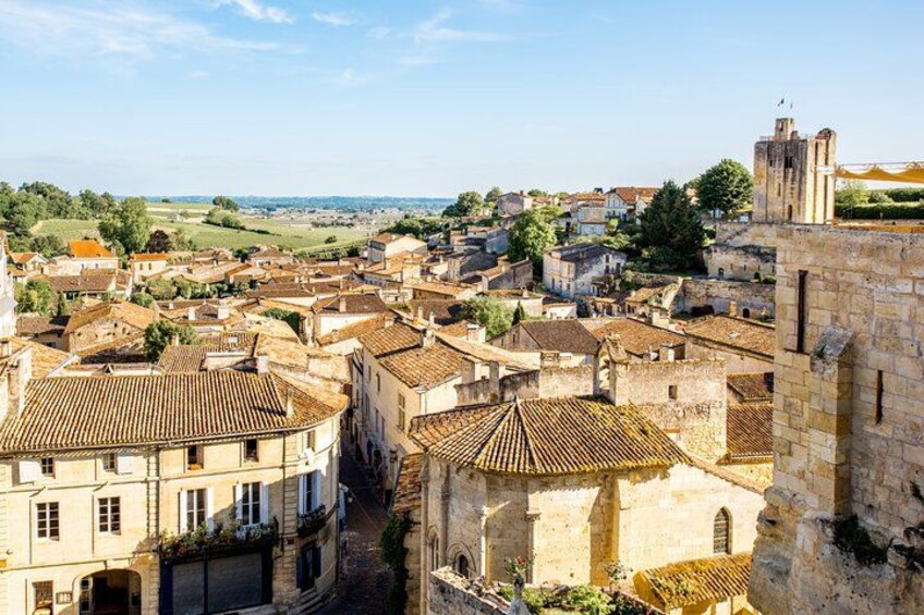 A historic town with stone buildings, a church, and a distant view of a castle. 3