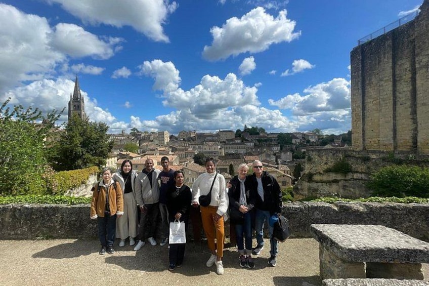 A group of people standing on a stone platform with a historic building and a church in the background. 2